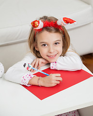 Image showing Smiling Girl Making Christmas Greeting Card