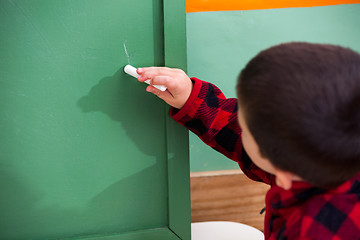 Image showing Boy Writing On Green Chalkboard In Preschool