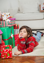 Image showing Boy Lying Besides Stacked Presents