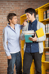 Image showing Male Student With Books Looking At Friend In Library