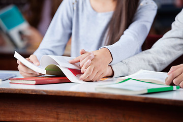 Image showing Teenage Couple Holding Hands At Table In Library