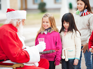 Image showing Santa Claus Offering Biscuits And Milk To Children