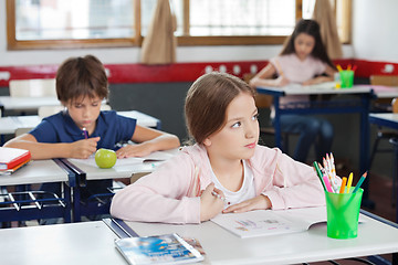 Image showing Schoolgirl Looking Away While Drawing In Classroom