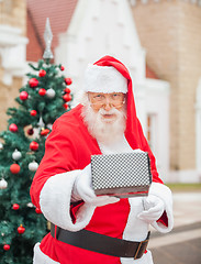 Image showing Santa Claus Giving Gift Against House