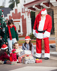 Image showing Santa Claus Looking At Children Opening Gifts