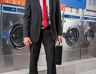 Image showing Businessman Holding Suitcase In Laundry