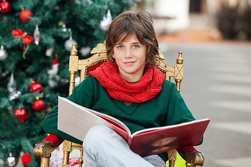 Image showing Boy With Book Sitting Against Christmas Tree