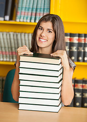 Image showing Beautiful Woman With Piled Books Smiling In Library