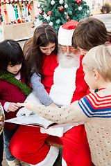 Image showing Santa Claus With Children Pointing At Book