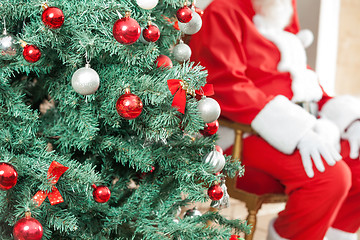 Image showing Decorated Christmas Tree With Santa Claus Sitting In Background