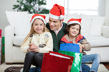 Image showing Siblings Sitting On Father's Lap With Christmas Presents