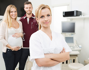 Image showing Confident Gynecologist With Expectant Couple In Background