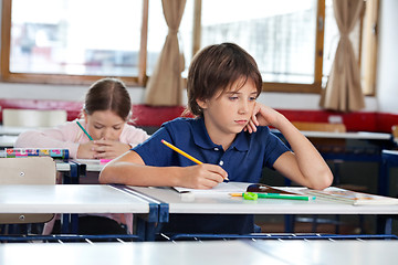 Image showing Boy Looking Away While Writing In Book