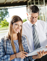 Image showing Student Holding Book While Standing With Teacher In College