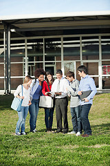 Image showing Students With Teacher Discussing Over Book On Campus