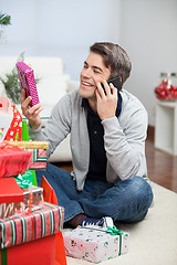 Image showing Man Holding Christmas Gift While Answering Mobilephone