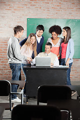 Image showing Students And Teacher Discussing Over Laptop In Classroom