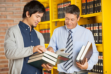 Image showing Student Holding Books While Discussing With Librarian In Library