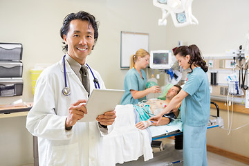 Image showing Doctor Holding Digital Tablet With Nurses Examining Patient