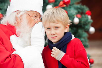 Image showing Santa Claus Whispering In Boy's Ear