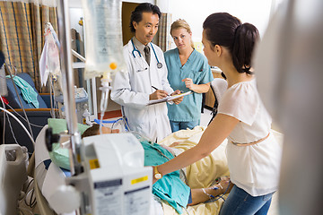 Image showing Woman Standing By Patient's Bed Looking At Doctor And Nurse