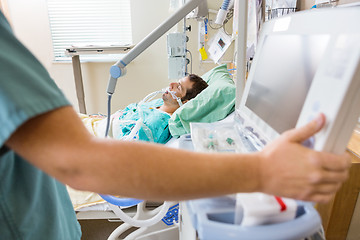 Image showing Nurse Pressing Monitor's Button With Patient Lying On Bed