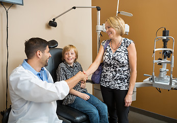 Image showing Optician And Woman Shaking Hands While Looking At Boy