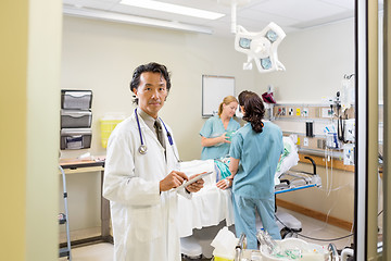 Image showing Doctor Holding Digital Tablet With Nurses Examining Patient