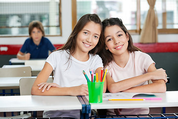 Image showing Cute Schoolgirls Sitting Together At Desk