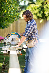 Image showing Carpenter Using Table Saw To Cut Wooden Plank At Site