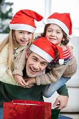 Image showing Playful Father Piggybacking Children During Christmas