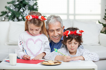 Image showing Grandfather Assisting Children In Writing Letters To Santa Claus