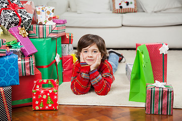 Image showing Boy Lying Besides Stacked Christmas Gifts