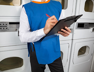 Image showing Male Helper Writing On Clipboard In Laundromat