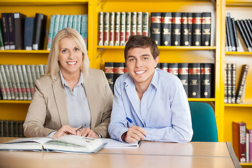 Image showing Student And Teacher With Books Sitting At Table In Library