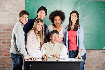 Image showing Professor And Students At Desk Against Greenboard In Classroom