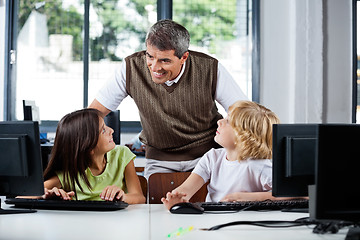 Image showing Teacher Assisting Schoolchildren In Using Desktop Pc