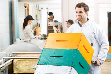 Image showing Beekeeper Holding Trolley Of Stacked Honeycomb Crates