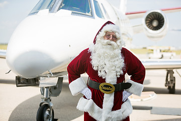 Image showing Santa With Hands On Hip Against Private Jet