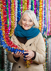 Image showing Senior Woman Holding Tinsels At Christmas Store