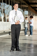 Image showing Mature Professor With Books Standing On College Campus