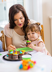 Image showing Mother With Girl Eating Cupcake At Birthday Party