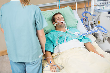 Image showing Patient Sleeping With Nurse Standing By