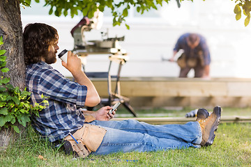 Image showing Carpenter Using Mobilephone While Drinking Coffee From Disposabl