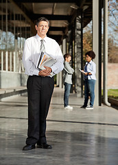 Image showing Mature Teacher With Books Standing On University Campus