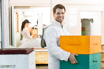 Image showing Male Beekeeper Carrying Stack Of Honeycomb Crates
