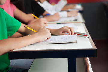 Image showing High School Students Writing On Paper At Desk