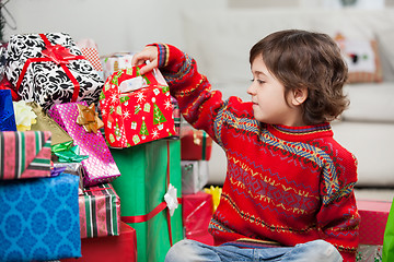 Image showing Boy Sitting By Stacked Christmas Gifts