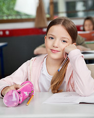 Image showing Schoolgirl Sitting With Pouch At Desk In Classroom