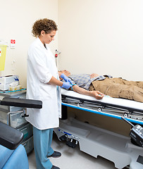 Image showing Doctor Tying Strap On Patient's Arm Before Blood Test